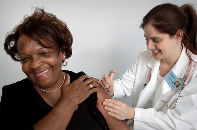 White woman doctor giving female lupus patient a flu shot