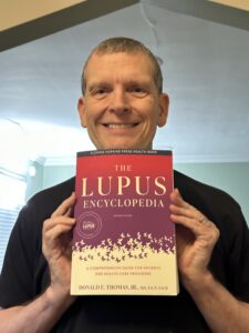 Dr. Donald Thomas MD holding the new edition Lupus Encyclopedia A Comprehensive Guide for Patients and Health Care Providers
